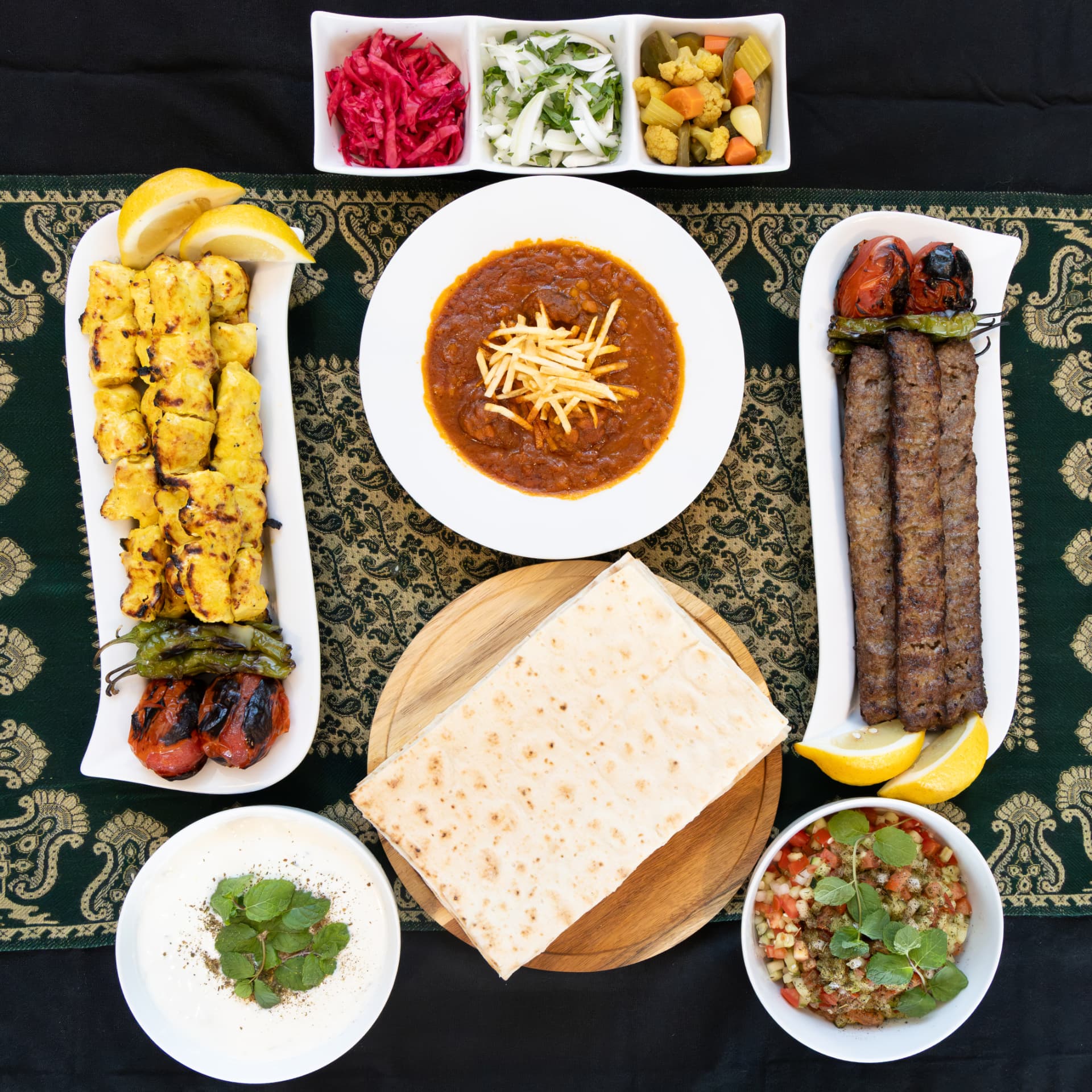 A Persian table with joojeh and koobideh kabobs, gheymeh, lavash, mast-o-khiar, and salad Shirazi