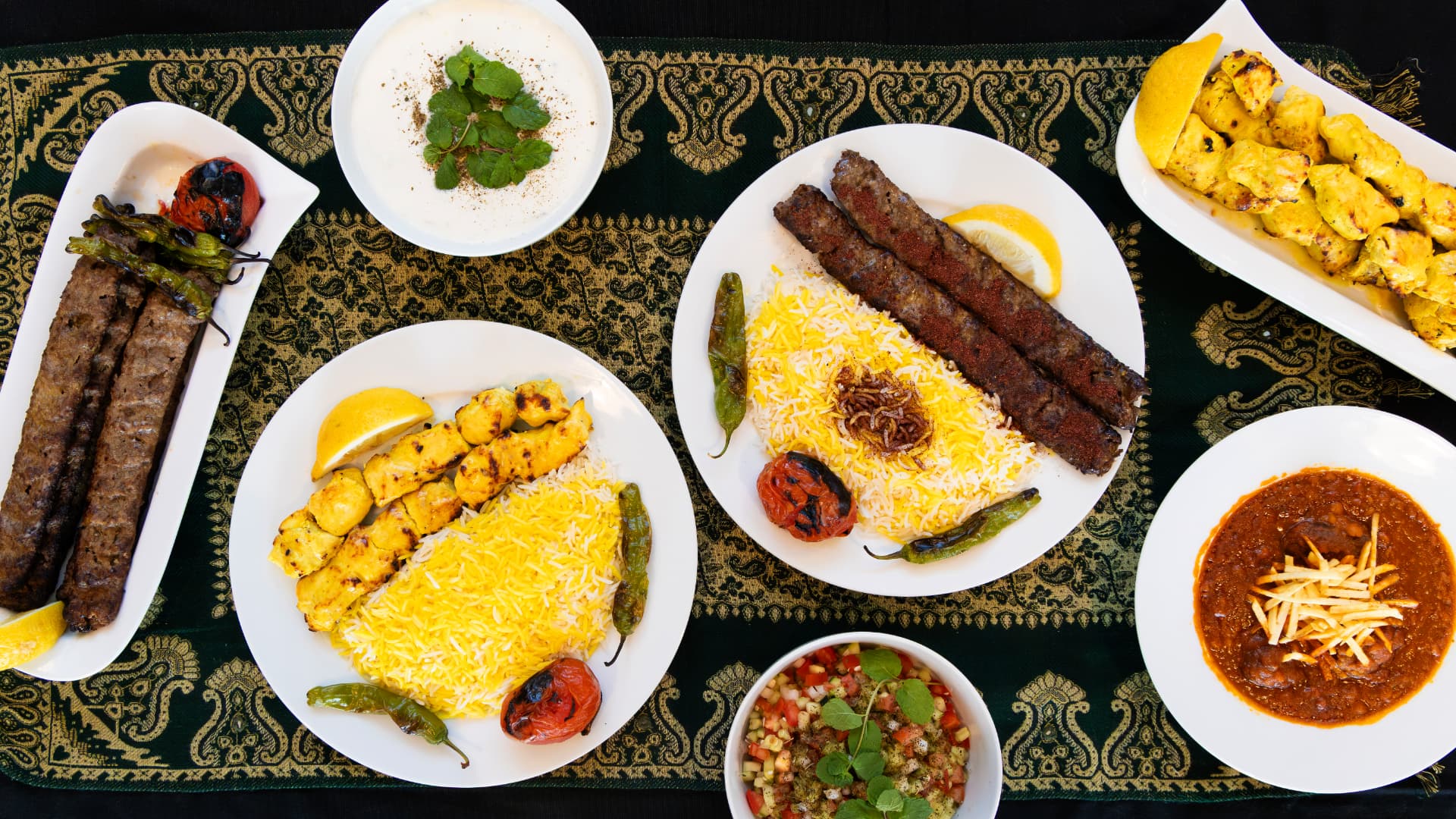 A full WhataKabob spread: koobideh and joojeh kabobs, saffron rice, gheymeh, and sides
